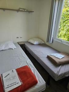 two beds sitting in a room with a window at Mobil-home climatisé (proximité EUROPA PARC) in Boofzheim