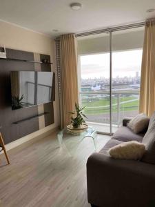 a living room with a couch and a large window at Dpto con hermosa vista al hipódromo de Monterrico in Lima