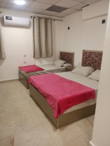 2 Betten in einem Zimmer mit roter Bettwäsche in der Unterkunft El jawhra house in Kairo