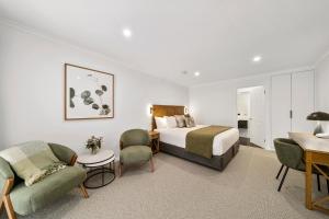 a hotel room with a bed and a desk and chairs at Beechworth Motor Inn in Beechworth