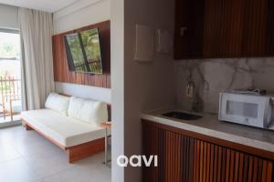 a kitchen and a living room with a couch and a microwave at Qavi - Luxo Rua Principal de Pipa #ÎledePipa in Pipa