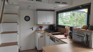 eine Küche mit weißen Schränken und einem großen Fenster in der Unterkunft Tiny House 14 - Sollberg in Salzhemmendorf