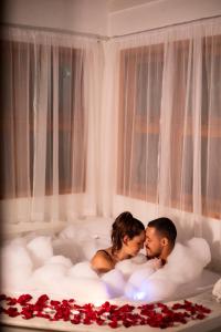 Un uomo e una donna seduti in una vasca da bagno con rose di Pousada O Cantinho da Raposa a Monte Verde