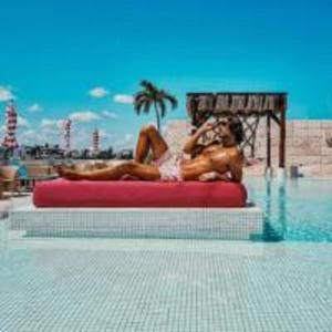 Dois homens nus deitados numa jangada numa piscina. em Hotel The Palm em Playa del Carmen