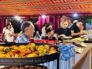 Bedouin host camp& with tour في وادي رم: مجموعة من الناس يجلسون على طاولة مع الطعام