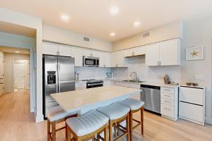 a kitchen with white cabinets and a kitchen island with bar stools at Sea Glass 208 in Gulf Shores