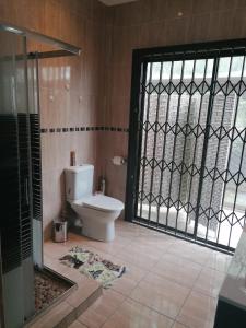 a bathroom with a toilet and a glass door at JB Countrylife Accommodation in Koedoe