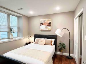 a bedroom with a bed with a black headboard and two windows at 405 Spacious and superior 1BDR APT in center city in Philadelphia