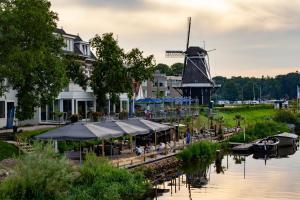 a restaurant with tables and umbrellas next to a windmill at De Zon Hotel & Restaurant by Flow in Ommen