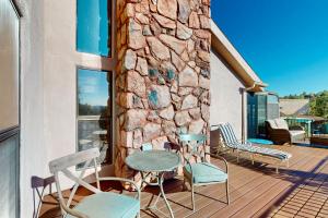 una terraza con sillas y una pared de piedra. en Yavapino Retreat en Sedona