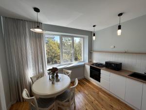 a kitchen with a table with chairs and a window at Dostyk in Almaty
