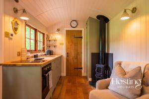 a kitchen with a stove top oven next to a couch at Red Kite Retreat - Allium - Shepherds Hut 2 in Henley on Thames