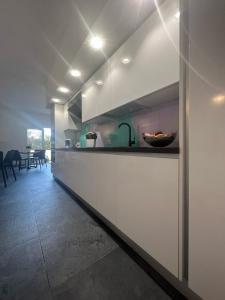 una cocina con armarios blancos y un bol de fruta en una barra en Acquamarina Luxury Rooms, en Budoni