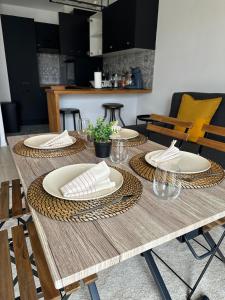 a wooden table with plates and napkins on it at L'envolée - 15' de Paris & 10' du Stade de France in Saint-Denis