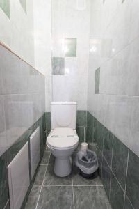 a bathroom with a white toilet in a green tiled wall at Самара in Petropavlovsk