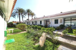 a house with a garden in front of it at Bungalow - Piscina climatizada - Playa del Inglés in Maspalomas