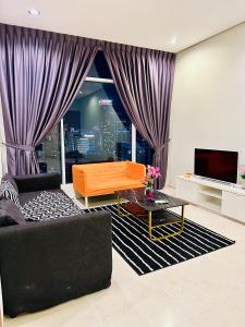 ein Wohnzimmer mit einem großen Fenster mit lila Vorhängen in der Unterkunft Soho Suites KLCC By Sky Multilink in Kuala Lumpur