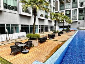 eine Terrasse mit Stühlen und Tischen neben einem Gebäude in der Unterkunft Soho Suites KLCC By Sky Multilink in Kuala Lumpur