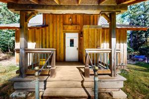 Cabaña de madera con puerta blanca y porche en The Canopy House, en Clinton