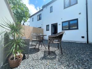 a patio with two chairs and a table and plants at Exceptional 3 bedroom home in Penzance~New~Seaside in Penzance
