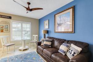 a living room with a brown leather couch and a ceiling fan at 105 Terraces at Beachside in Fernandina Beach