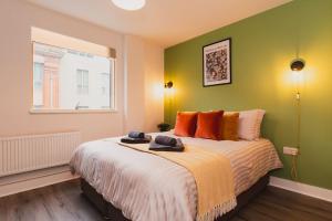 a bedroom with a large bed with orange and green walls at Stunning Brand New One Bed City Apartment in Leicester