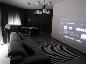 a living room with a couch and a projection screen at Apartamento minimalista Centenário in São Brás de Alportel