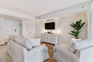 sala de estar con 2 sillas blancas y TV de pantalla plana en 201 Terraces at Beachside, en Amelia Island
