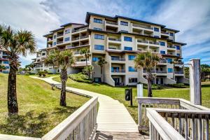a large apartment building with palm trees and a walkway at 291 Sandcastles in Amelia Island