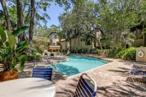 einen Pool mit einem Tisch, Stühlen und Bäumen in der Unterkunft 2349 Courtside Villas in Amelia Island