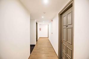 - un couloir avec une porte, des murs blancs et du parquet dans l'établissement Townhouse HOTEL CLOUD BAY, à Gurgaon
