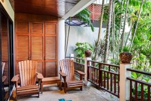 einen Balkon eines Hauses mit Stühlen und Bäumen in der Unterkunft The Sands 2 bedroom apartment Naiharn in Nai Harn Beach