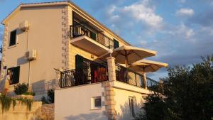 a building with a balcony with umbrellas on it at Apartments Kate in Nečujam