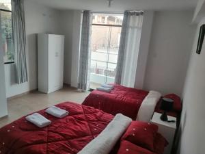 纳斯卡Alemar's House的一间卧室设有两张带红色床单的床和窗户。