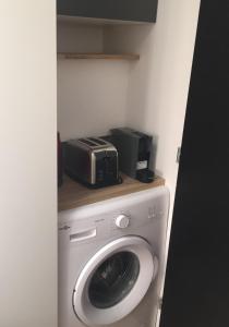 eine Waschmaschine mit einer Mikrowelle darüber in der Unterkunft Le Mini Montesquieu Studio Cosy 2 pers in Lyon