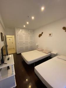 a white room with two beds and a television at Blife Sun Hostel in Faro