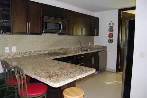 eine Küche mit einer Theke mit Spüle und Mikrowelle in der Unterkunft Casa Adams Torre 13-202 Mayan Lakes Resort in Playa Encanto