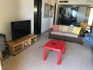 ein Wohnzimmer mit einem roten Stuhl vor einem TV in der Unterkunft Casa Adams Torre 13-202 Mayan Lakes Resort in Playa Encanto