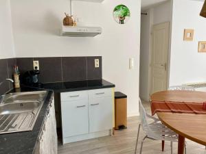 a kitchen with a sink and a table with a dining room at Accueillant petit T2 cœur de centre ville in Lézignan-Corbières +3 photos