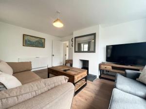 a living room with a couch and a flat screen tv at Bright Bungalow with 3 bedrooms and Garden in Porthlevan in Porthleven