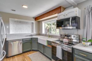 a kitchen with green cabinets and a large window at Chic Columbia City Vacation Rental with Kayaks! 