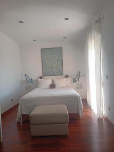 a white bedroom with a white bed and a chair at Habitación con vistas in Aguadulce