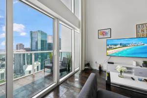 a living room with a large tv and large windows at Amazing Loft Style 1 Bedroom In Brickell Miami in Miami