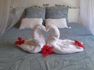 two swans are making a heart shape on a bed at Chez Mélanie in Sainte-Rose