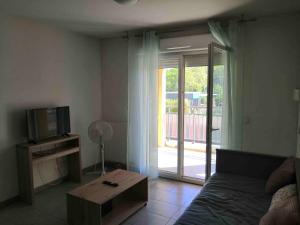 a living room with a couch and a television and a table at Appartement T2 - Golf de Fontcaude - Résidence Coté Green à Juvignac 34990 in Juvignac