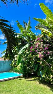einen Garten mit Blumen neben einem Pool in der Unterkunft Castelo Pink Boutique Hotel in Uruau