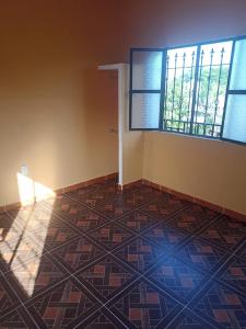 um quarto vazio com piso em azulejo e duas janelas em cuartos en renta El portón azul em Ixtepec