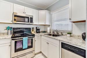 una cucina con mobili bianchi, fornelli e lavello di 2810 Ohio Avenue #2 ad Amelia Island Altre 23 foto