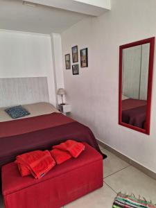 1 dormitorio con cama roja y espejo en Dptos Novas en Junín