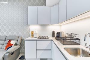 a kitchen with white cabinets and a sink at bnbmehomes - Modern Luxury Studio in heart of JVC - 419 in Dubai